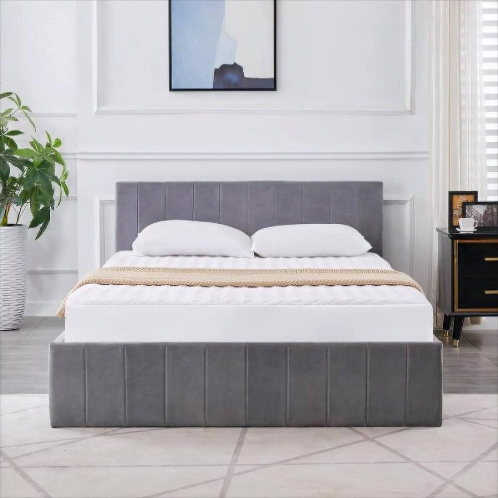 Grey velvet ottoman bed with a gas lift storage feature, featuring a line pattern, 3ft single size, paired with a white mattress, set in a modern bedroom with a plant and artwork.