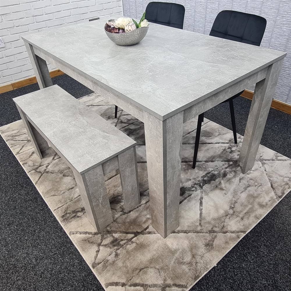 Grey dining table set featuring a rectangular table, two black chairs, and a matching bench, all with a textured finish, placed on a patterned rug.