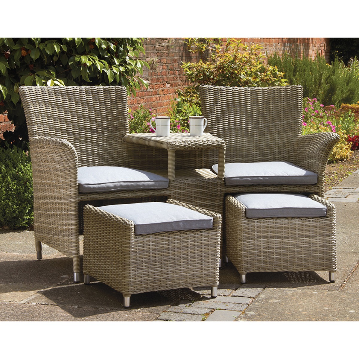 Cream-colored wicker companion set featuring two armchairs with gray cushions, a small side table, and two footstools, perfect for outdoor relaxation.
