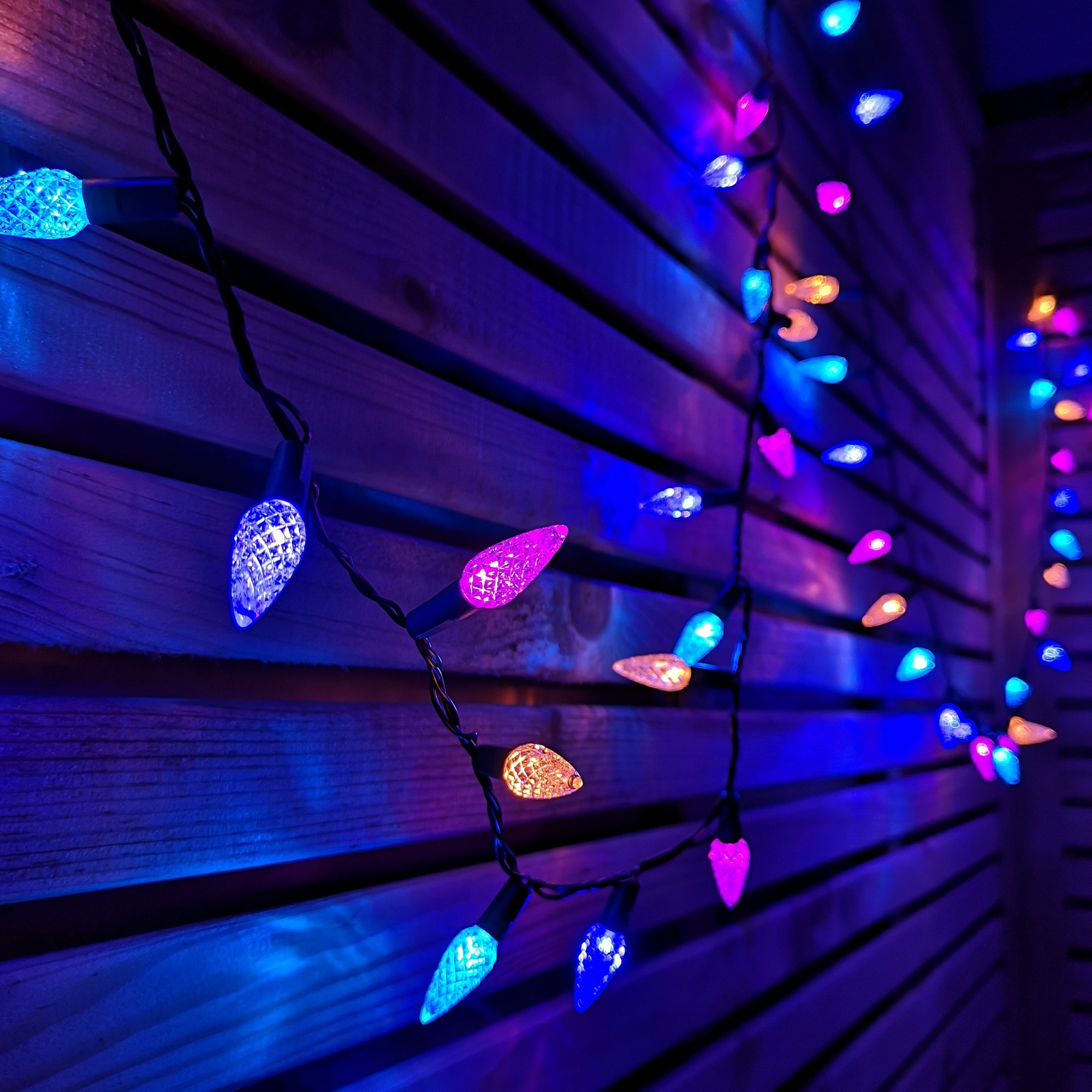 Colorful 7.5m string lights featuring 150 LED pine cone-shaped bulbs in vibrant rainbow hues, set against a wooden backdrop.