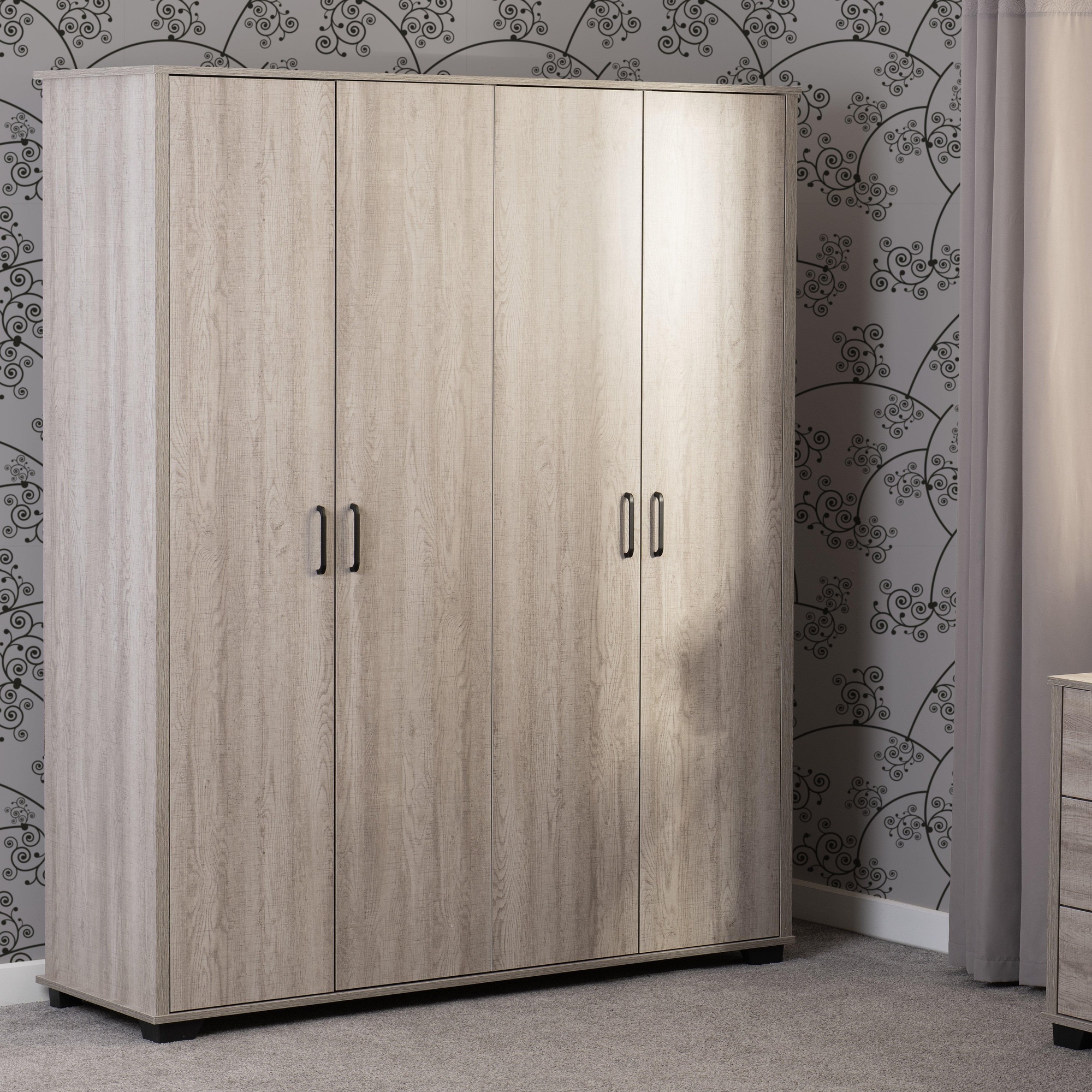 Light oak effect wardrobe with four doors, featuring sleek black handles and a minimalist design, set against a patterned wall and carpeted floor.