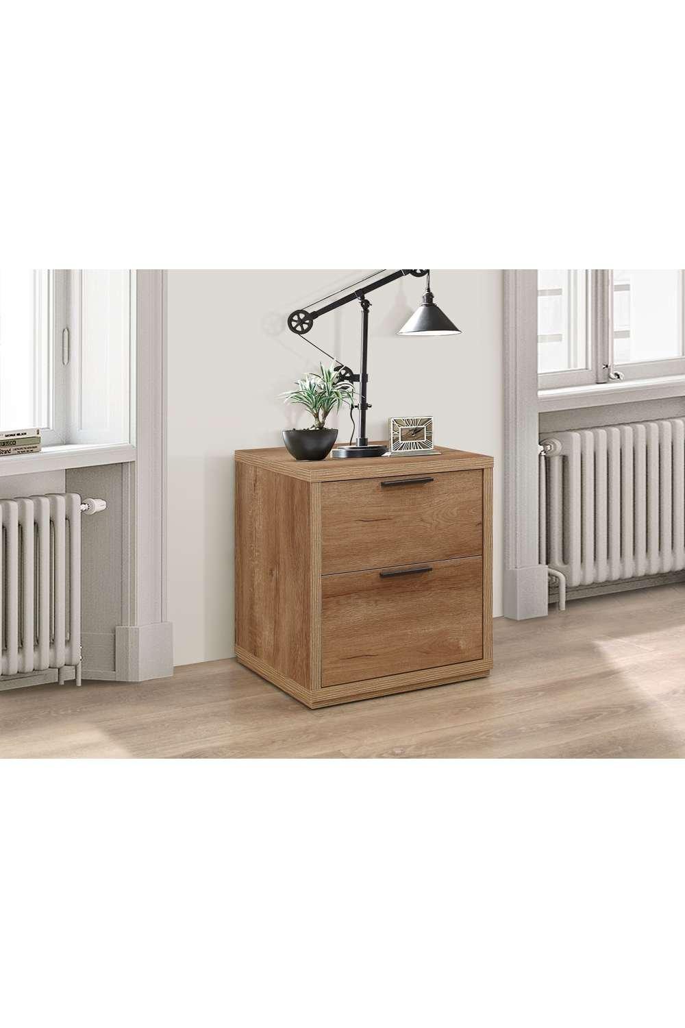 Rustic oak bedside table in brown with two drawers, featuring a sleek black handle, placed beside a modern lamp and a small plant against a neutral wall.