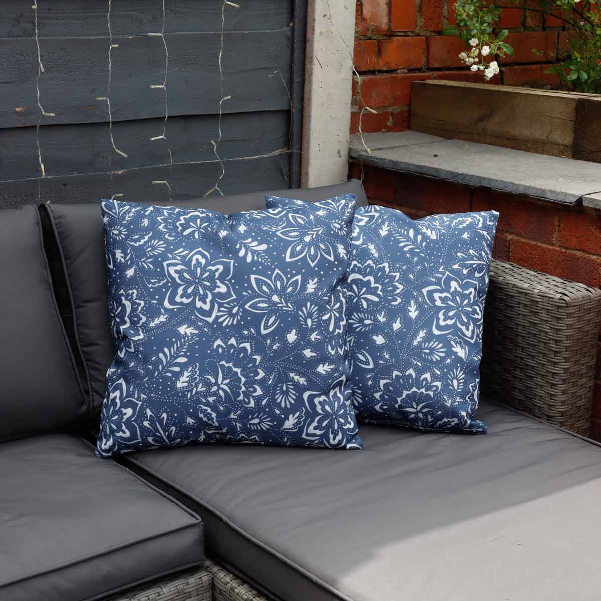 Blue outdoor cushions with a floral pattern, made of durable fabric, filled for comfort, placed on a gray sofa in a cozy outdoor setting.