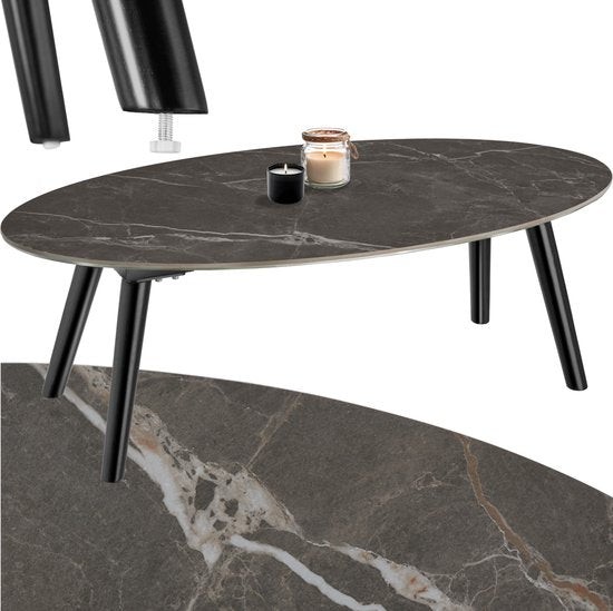 Oval coffee table with a black marble top, featuring a sleek design and sturdy black wooden legs, complemented by a candle and decorative items on the surface.