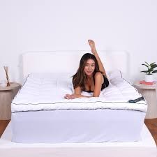 White velvet touch mattress enhancer by The Lyndon Company, designed for super king size beds, featuring a soft texture and elegant design, with a model lounging on it.