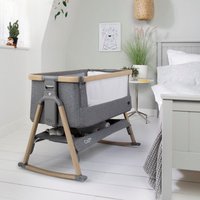 Oak and charcoal bedside crib with mesh sides, wooden legs, and storage shelf, designed for infant sleep safety.