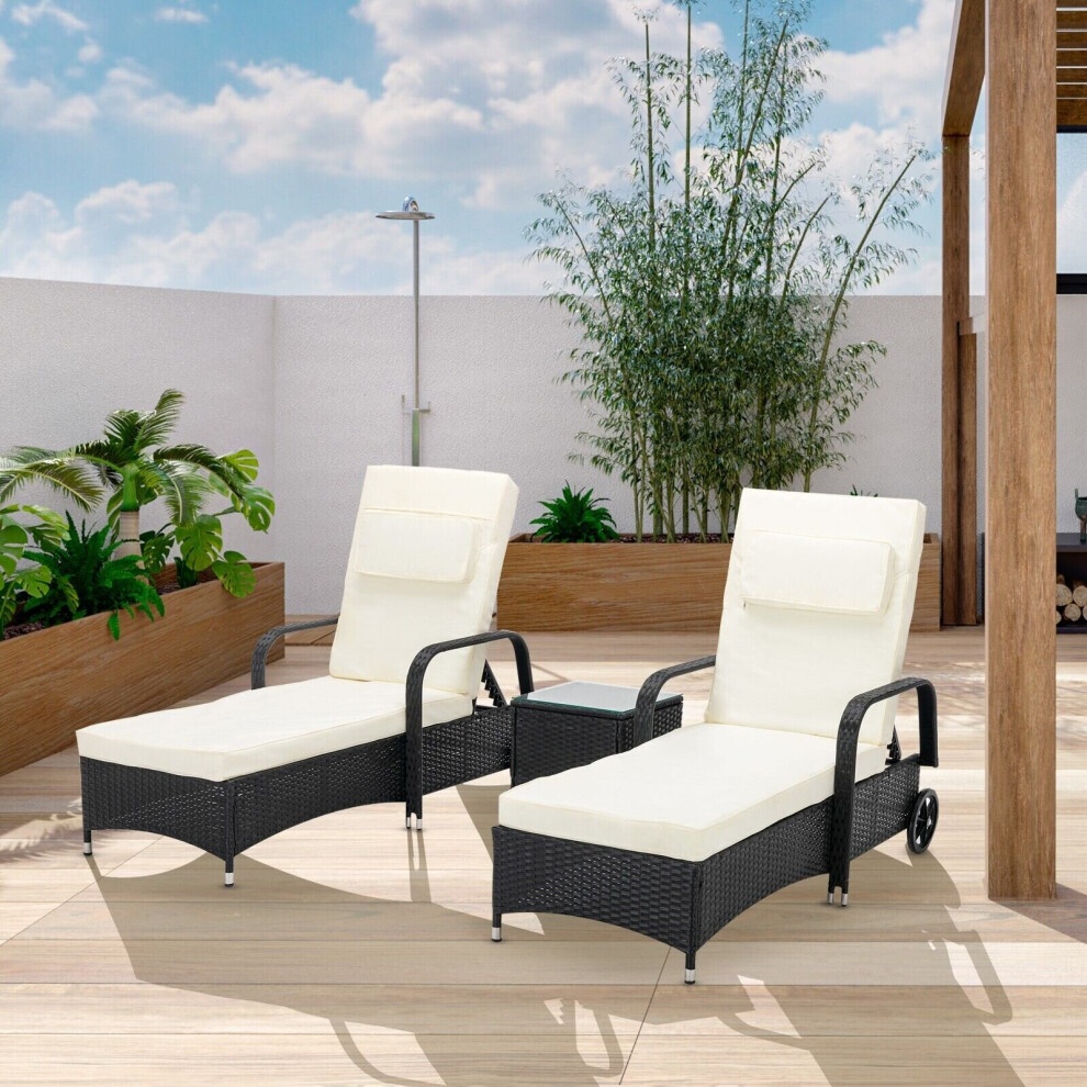 Black rattan sun lounger bed recliner set featuring two adjustable chairs with cream cushions and a matching side table, set against a sunny outdoor backdrop with greenery.