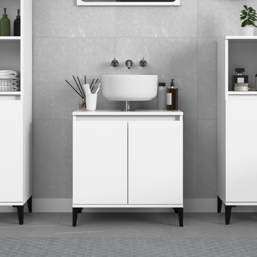 White engineered wood sink cabinet with two doors, minimalist design, black legs, and a round white sink on top, set against a grey tiled wall.