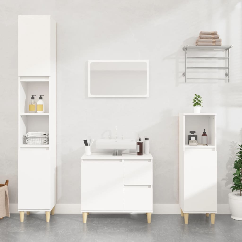 White engineered wood bathroom cabinet with two drawers and open shelves, complemented by a matching tall cabinet and a mirror, all featuring minimalist design and light wood legs.