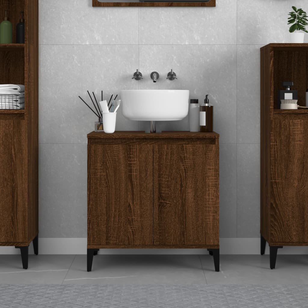 Brown oak sink cabinet made of engineered wood, featuring a white basin, sleek design, and black legs, set against a light gray tiled wall with decorative shelves.
