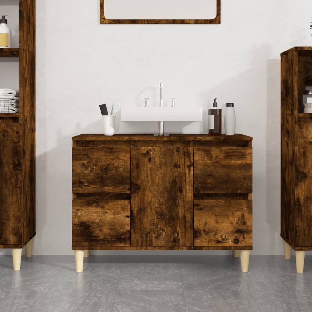 Smoked oak sink cabinet in engineered wood, featuring a sleek design with two doors, a white sink on top, and light-colored legs, set against a neutral wall.