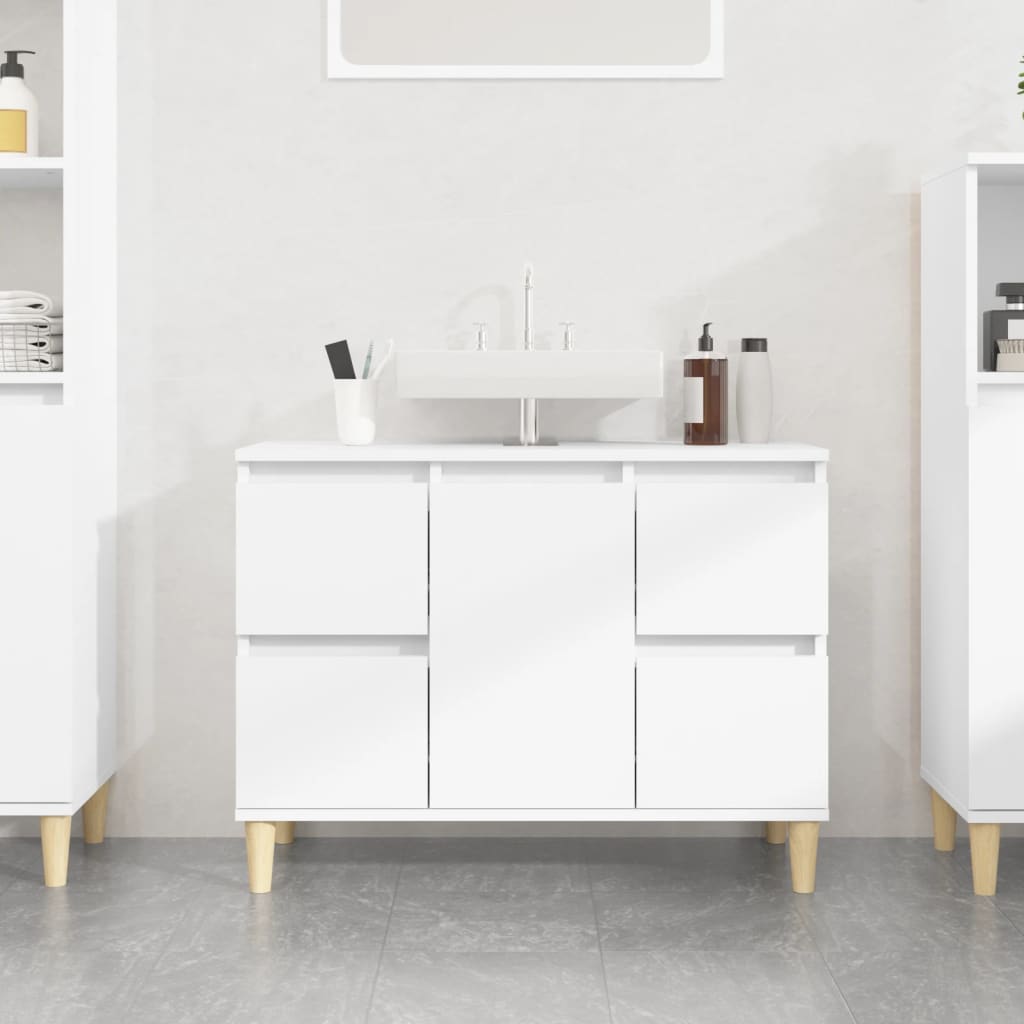 White sink cabinet made of engineered wood, featuring four drawers and a central open space, supported by light wooden legs, ideal for bathroom storage.