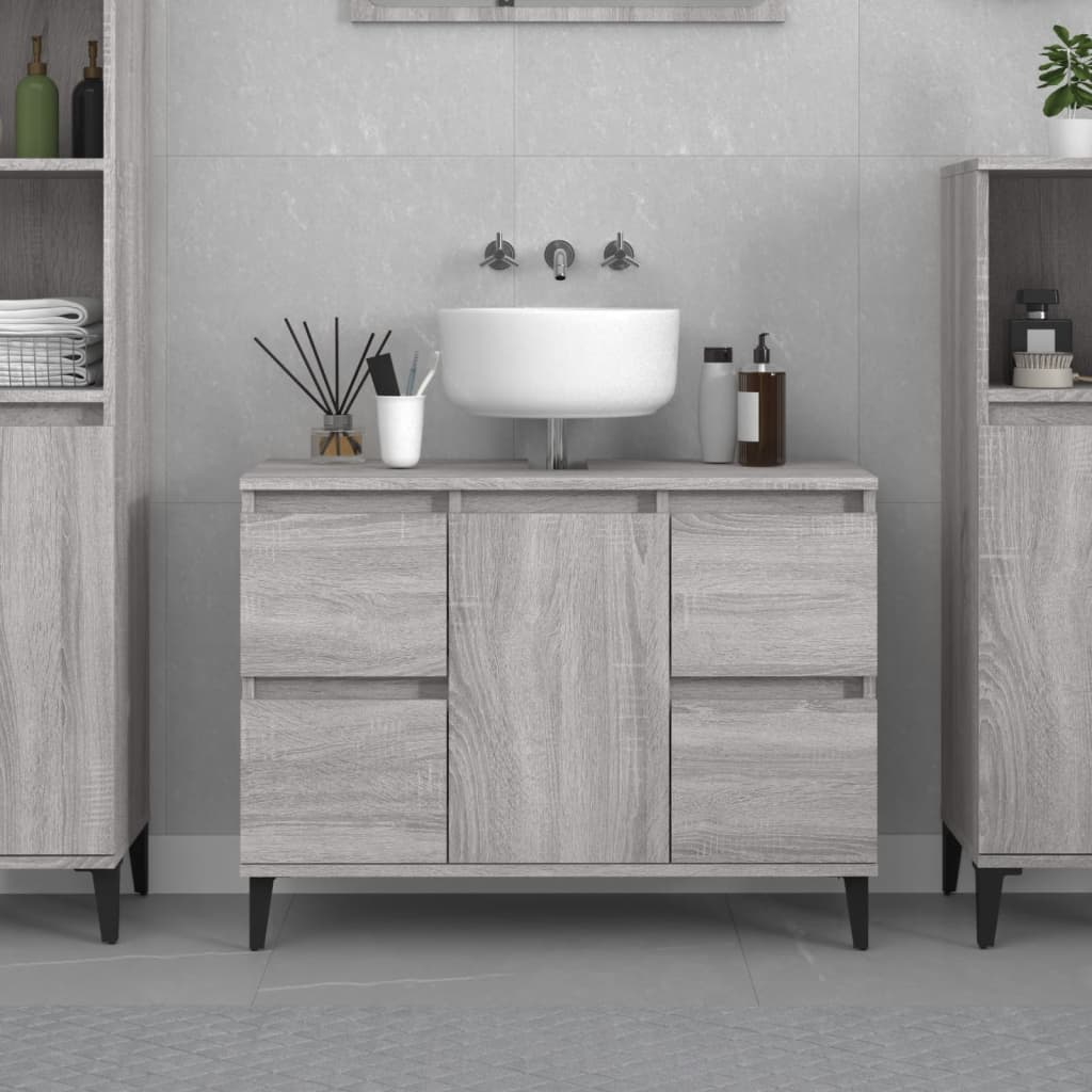 Grey Sonoma sink cabinet made of engineered wood, featuring a smooth countertop, a round white sink, four storage drawers, and sleek black legs, set against a light tiled background.