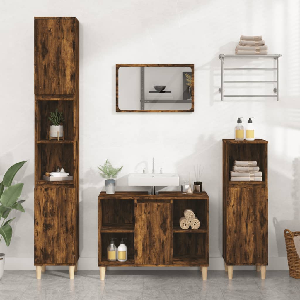 Sink cabinet in smoked oak finish, featuring two doors, open shelves, and wooden legs, complemented by a matching tall cabinet and mirror, set against a light-colored wall.