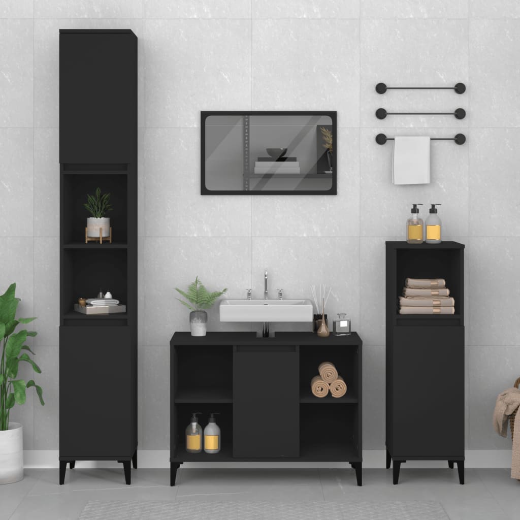 Black sink cabinet made of engineered wood, featuring two doors, open shelves, and sleek legs, complemented by matching tall storage units and a mirror in a modern bathroom setting.