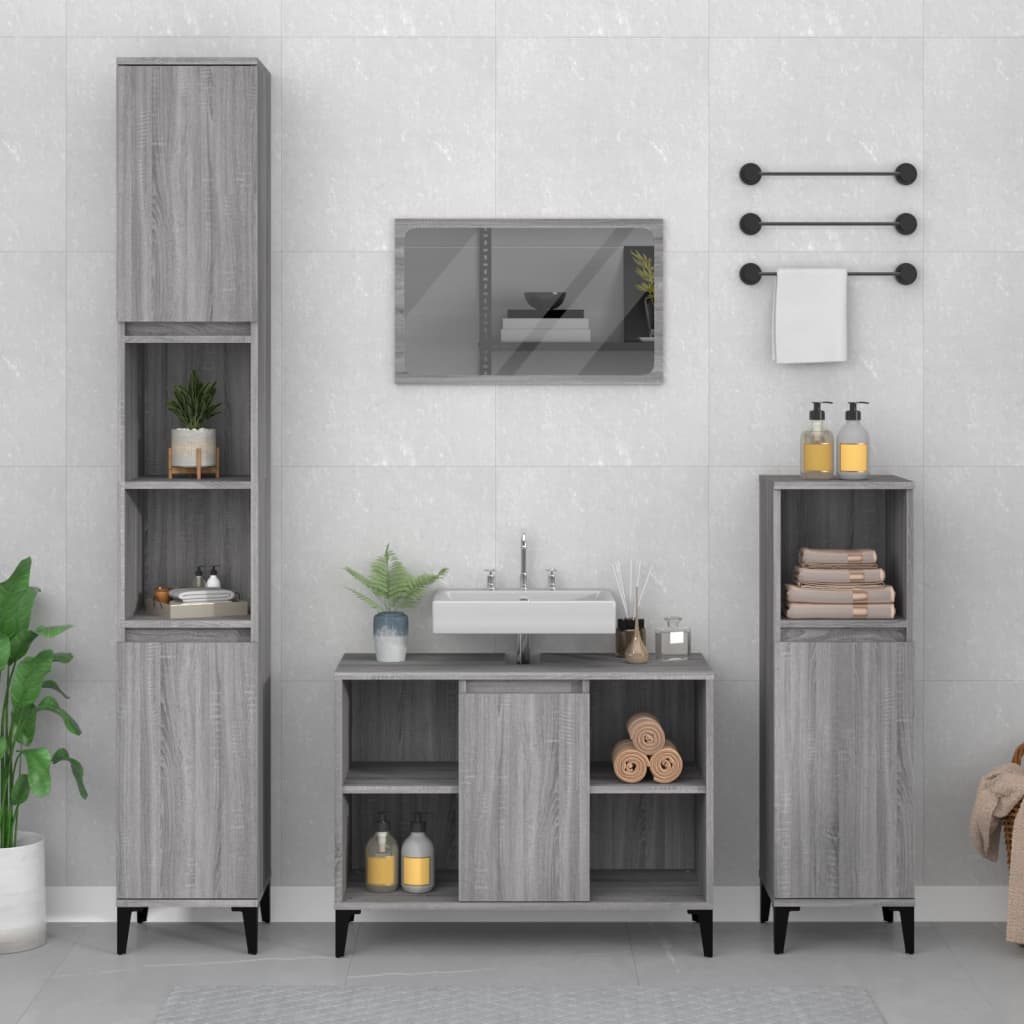 Grey Sonoma sink cabinet made of engineered wood, featuring a sleek design with open shelves, a central sink area, and elegant black legs, complemented by decorative plants and toiletries.