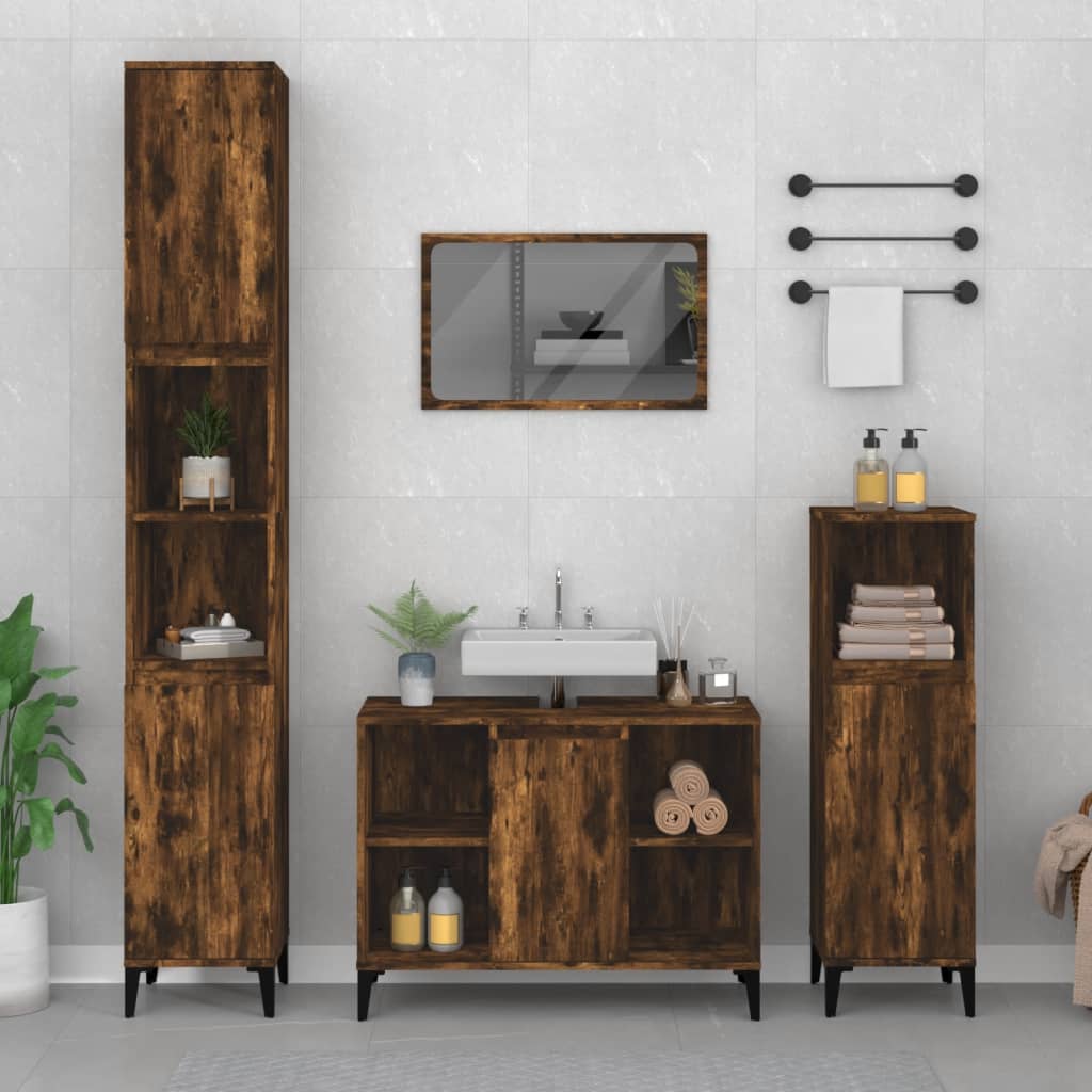 Sink cabinet in smoked oak finish, featuring engineered wood construction, two doors, open shelves, and sleek black legs, complemented by matching tall cabinets and a mirror.