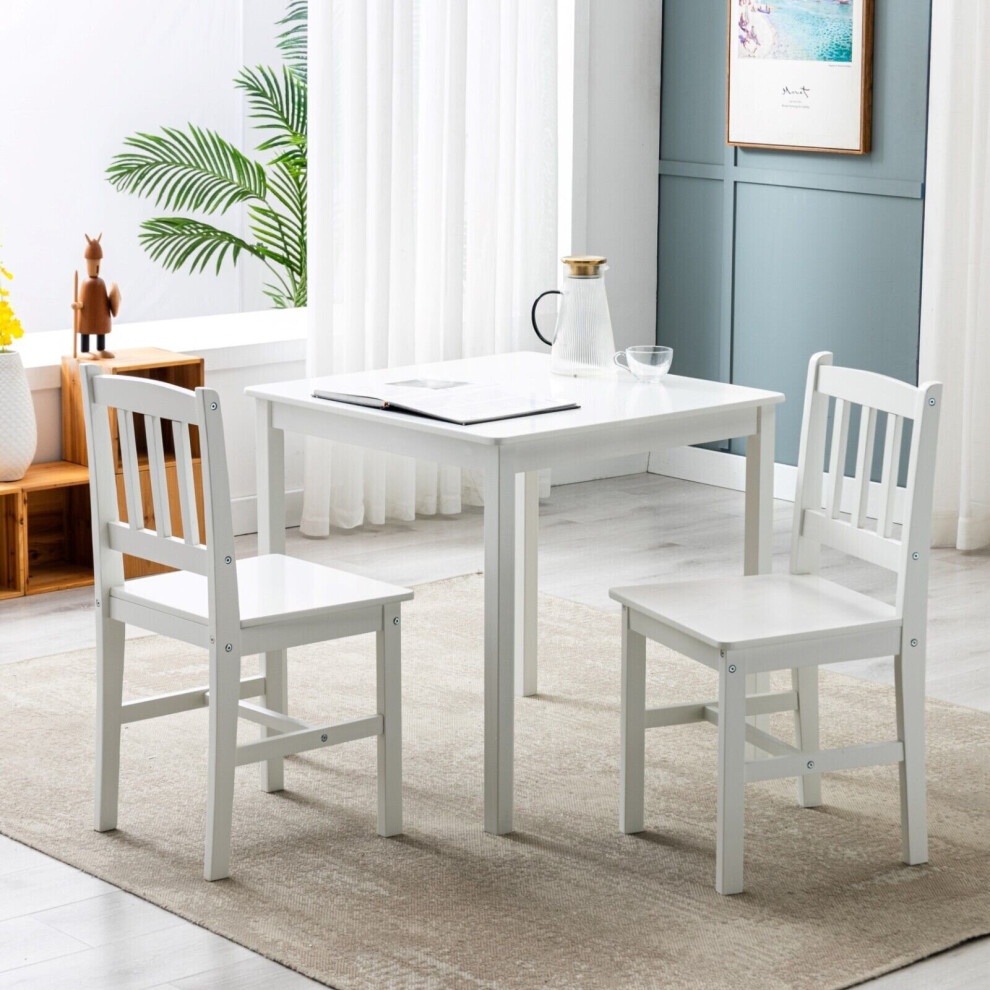 Classic solid white wooden dining table with two matching chairs, featuring a simple design, square table top, and sturdy construction, set against a light-filled room.