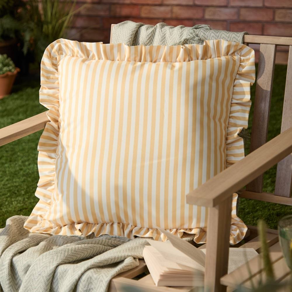 Yellow and white striped outdoor cushion with ruffled edges, made of durable fabric, placed on a wooden chair in a garden setting.