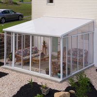 White Palram Canopia lean-to conservatory with clear panels, attached to a house, featuring a sloped roof and sliding doors.