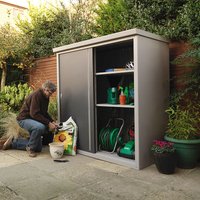 Gray Trimetals Guardian D63 metal storage shed with sliding doors, shelves, and garden tools inside.
