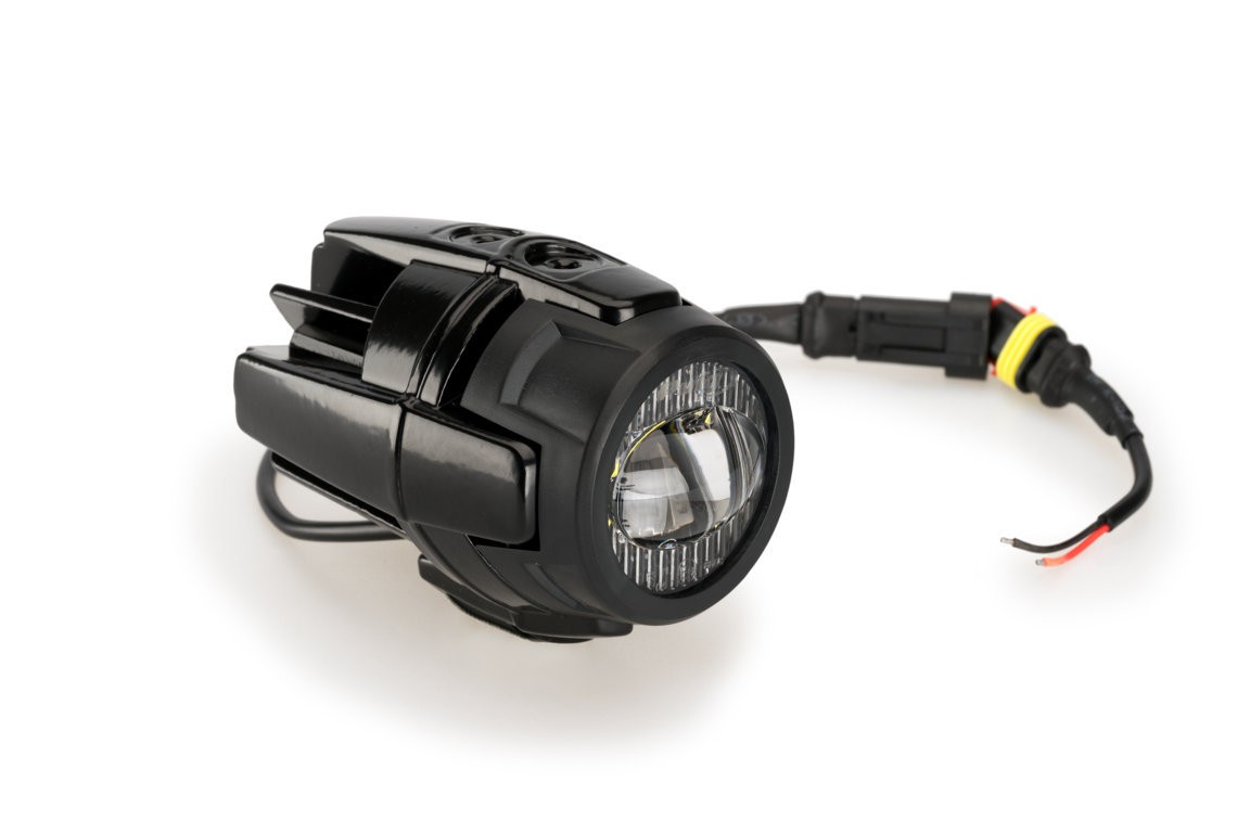 Black Puig Beam Auxiliary Light featuring a round lens with a chrome ring, mounted on a sleek black housing, with wiring for easy installation on KTM 1050 Adventure models.