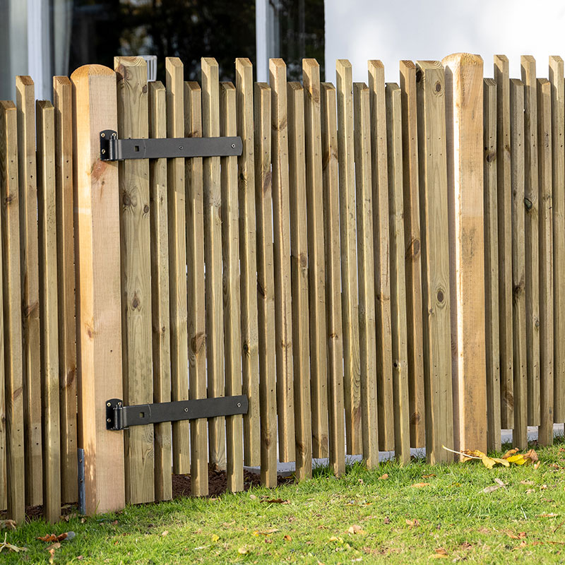 3ft high contemporary picket gate made of natural wood with vertical slats, featuring black metal hinges and a sturdy frame, set against a grassy area and modern building backdrop.