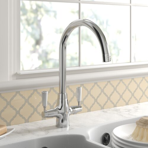 Aquaclassic 2 Dual Lever Monobloc Tap in a sleek chrome finish, featuring a curved spout and two lever handles, installed above a kitchen sink with a patterned backsplash.