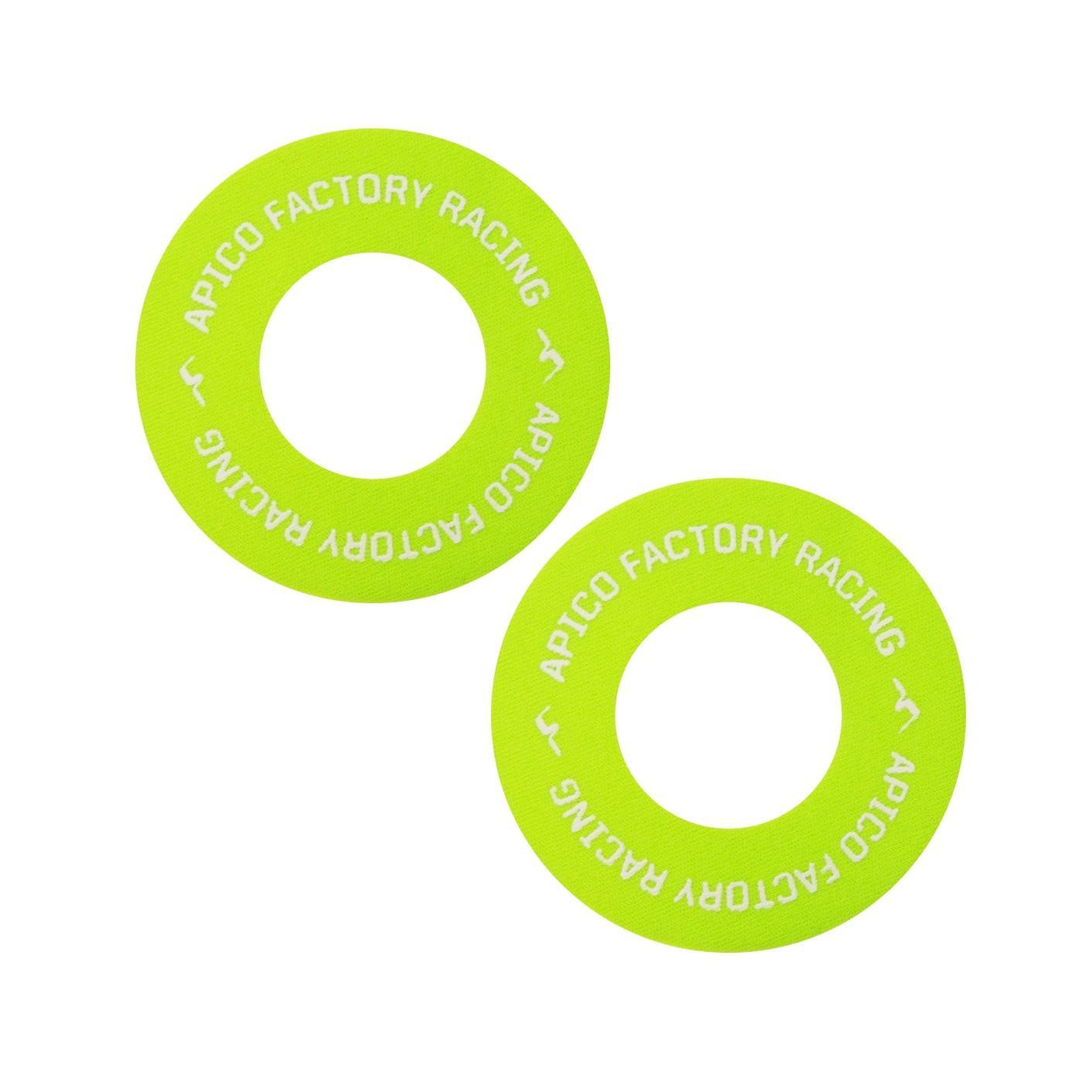 Two green and white rubber grip donuts, featuring "APICO FACTORY RACING" printed in white text around the outer edge, designed for enhancing grip on handlebars.