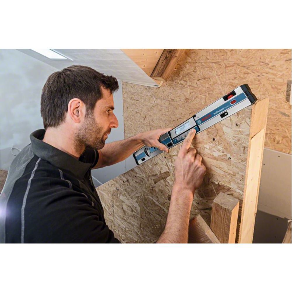 Bosch GIM60 L digital inclinometer laser level in use, featuring a metallic body with a digital display, red and blue buttons, and a user adjusting it against a wooden surface.