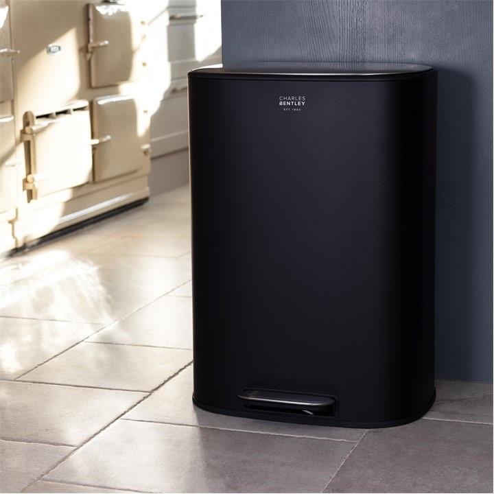 Sleek black 50L pedal kitchen bin by Charles Bentley, featuring a smooth matte finish and a foot pedal for hands-free operation, positioned against a wall in a modern kitchen setting.