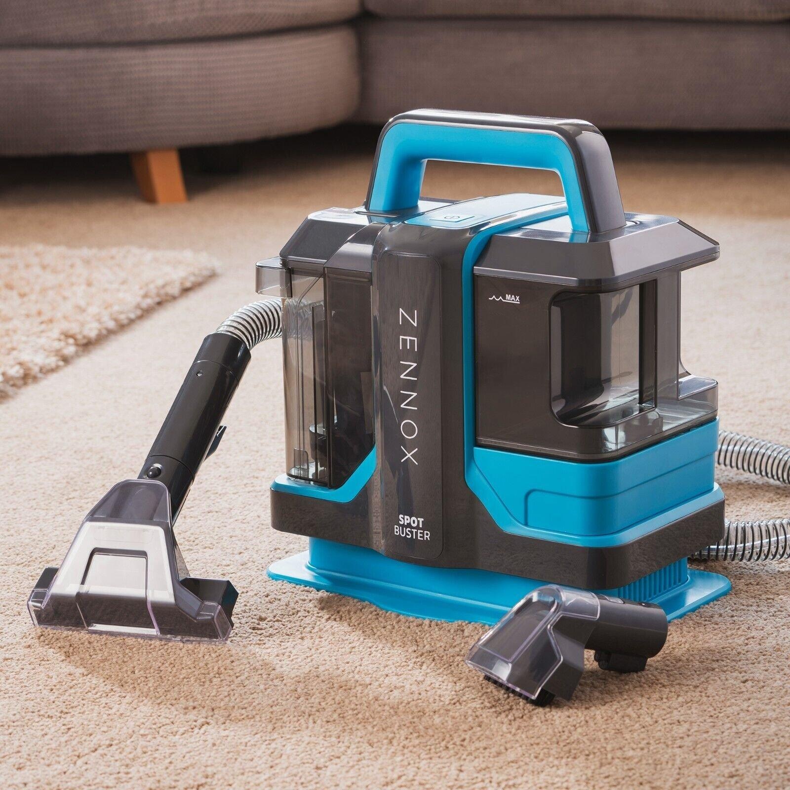 Cooks Professional Zennox Spot Buster Carpet Cleaner in blue and gray, featuring a transparent water tank, detachable hose, and multiple cleaning attachments, placed on a beige carpet.