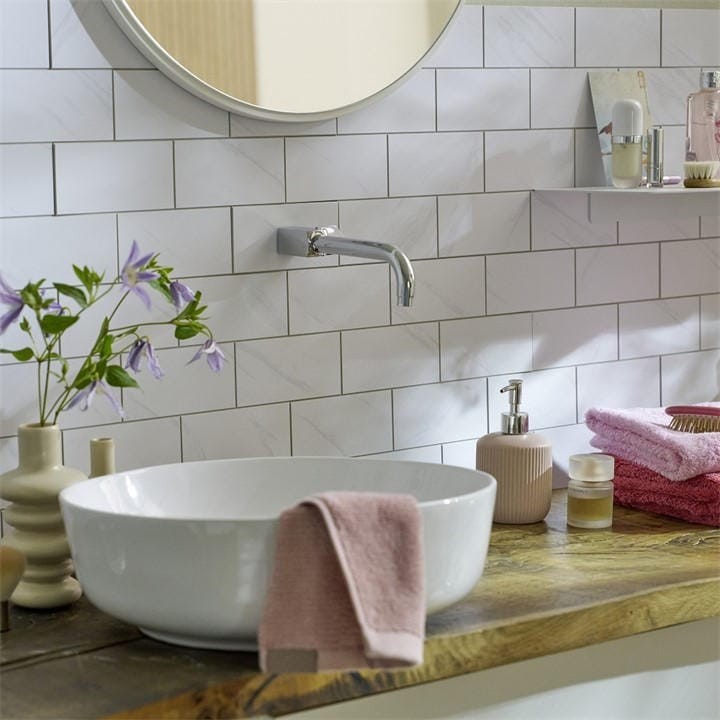 Self-adhesive premium wall tiles in grey marble finish, featuring a sleek design, complementing a modern bathroom with a round mirror and stylish decor.