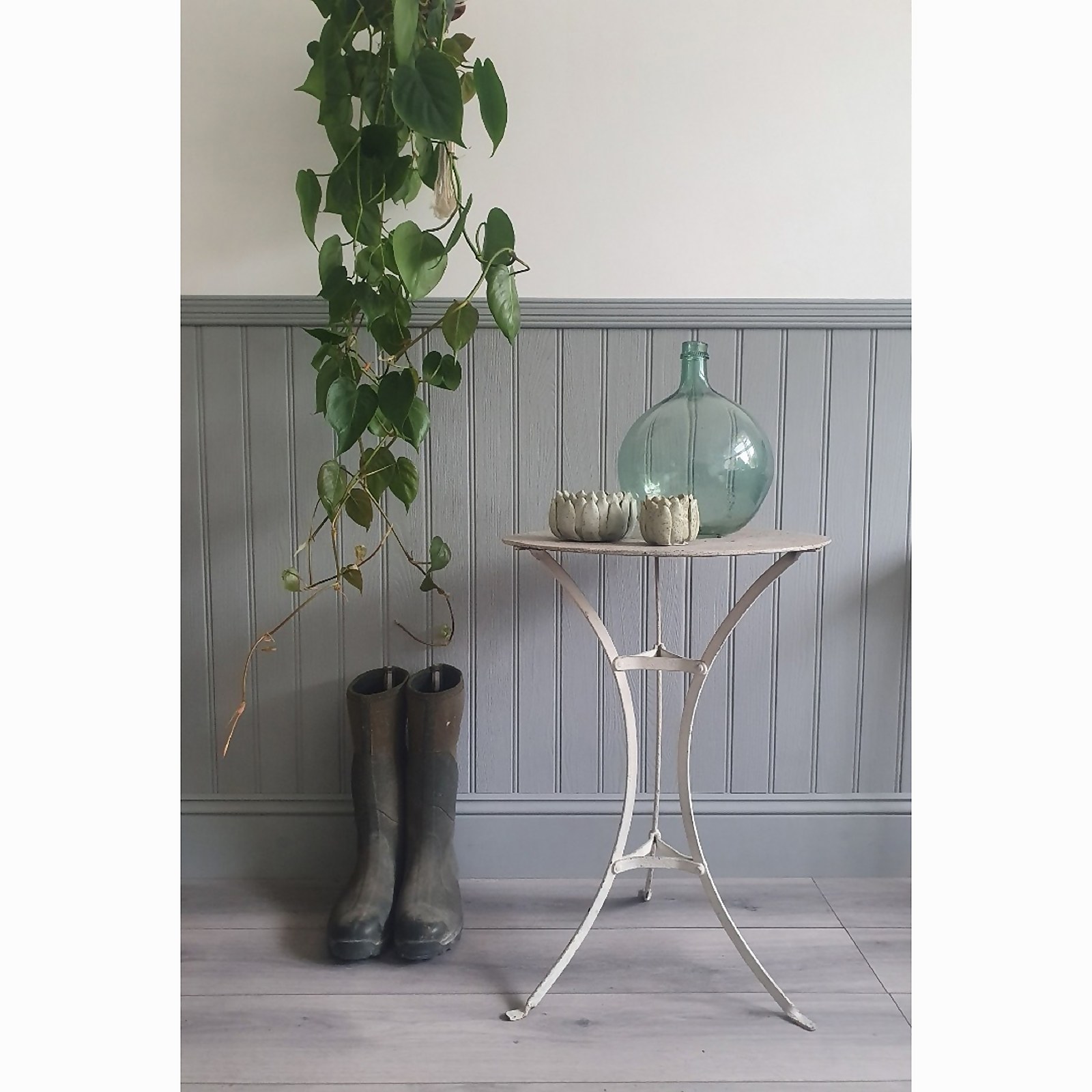 EASIpanel Tongue and Groove MDF wall panel in a soft grey color, featuring vertical grooves, paired with rustic decor including a glass vase and potted plants.