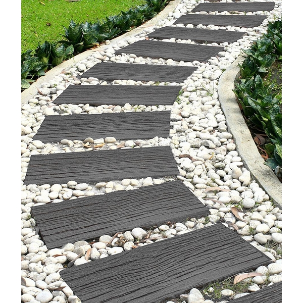 Grey railroad stepping stones made of eco-friendly material, arranged in a winding path surrounded by small white pebbles and green foliage.