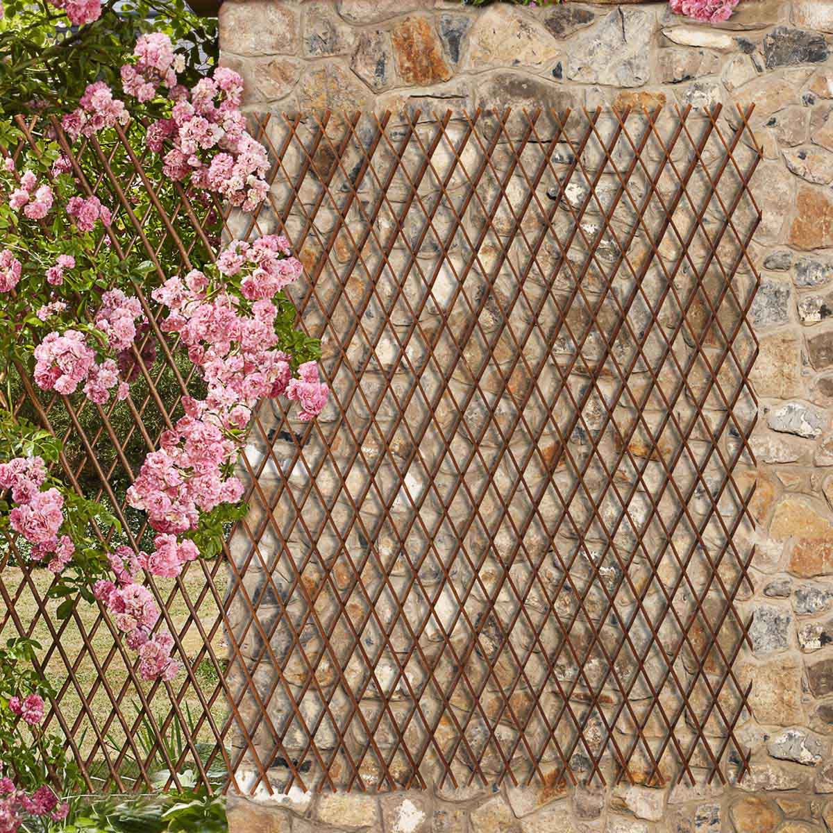 Two brown willow trellis panels, each measuring 180 x 60 cm, feature a diamond lattice design, set against a stone wall and surrounded by pink flowering plants.