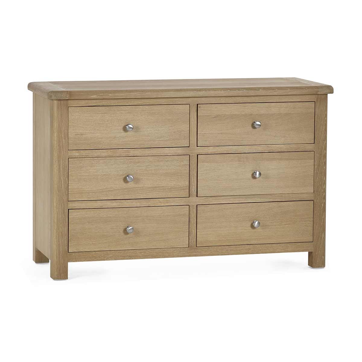 Limed oak wide chest with six spacious drawers, featuring a smooth surface, rounded edges, and silver knobs for easy access, showcasing a light, natural wood finish.