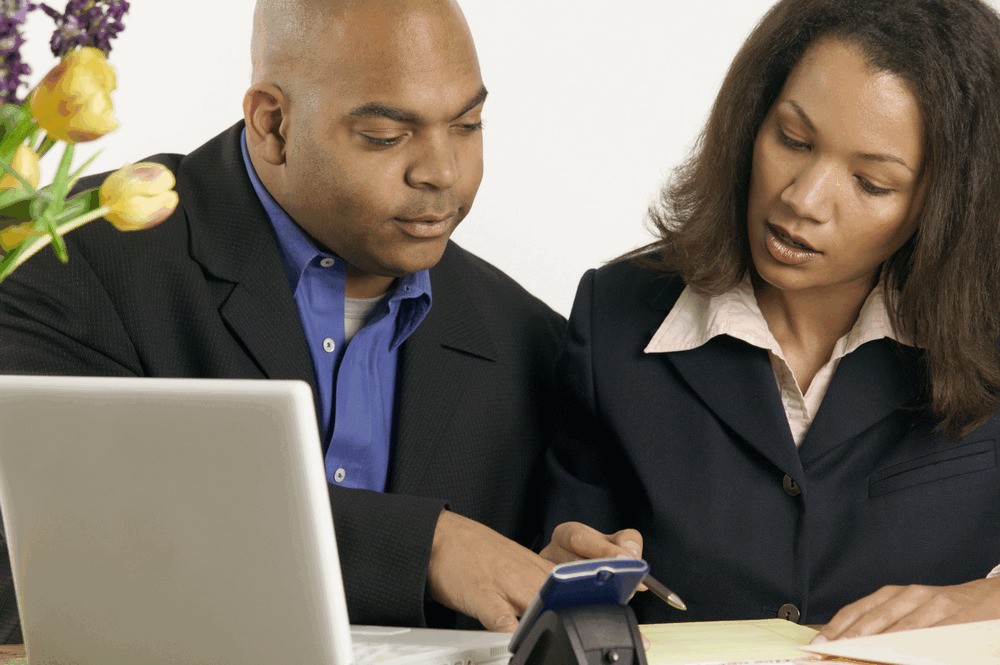 Keytools 1/2 Day Training Voucher displayed with two professionals discussing over a laptop, featuring a blue folder and a pen, set against a light background with flowers.
