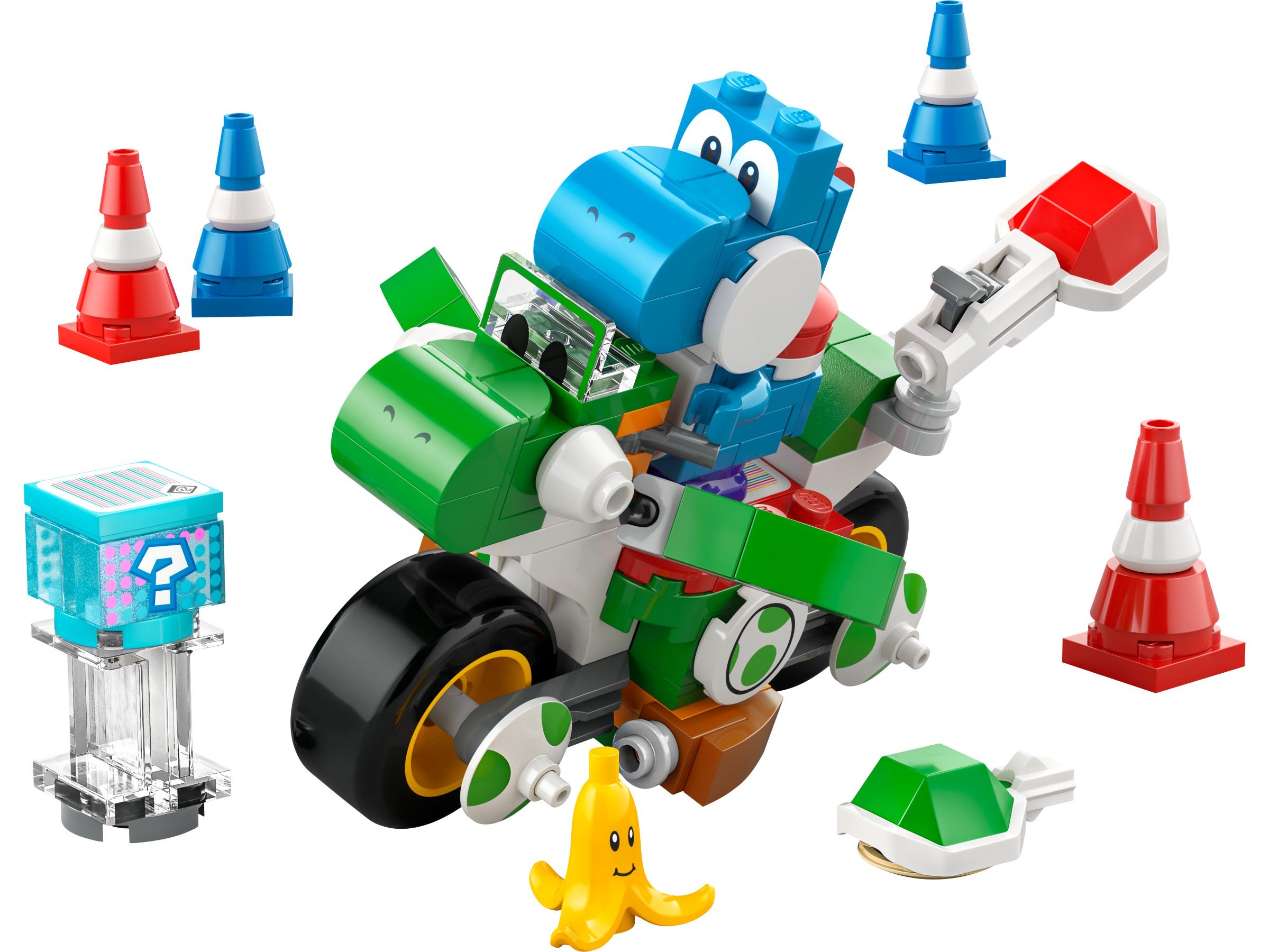 Yoshi-themed bike toy in green and blue with large wheels, featuring a mini Yoshi figure, banana, and various colored traffic cones and items.