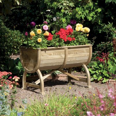 Wooden barrel-shaped planter with a natural finish, featuring vibrant flowers in various colors, supported by curved wooden legs, set in a lush garden environment.