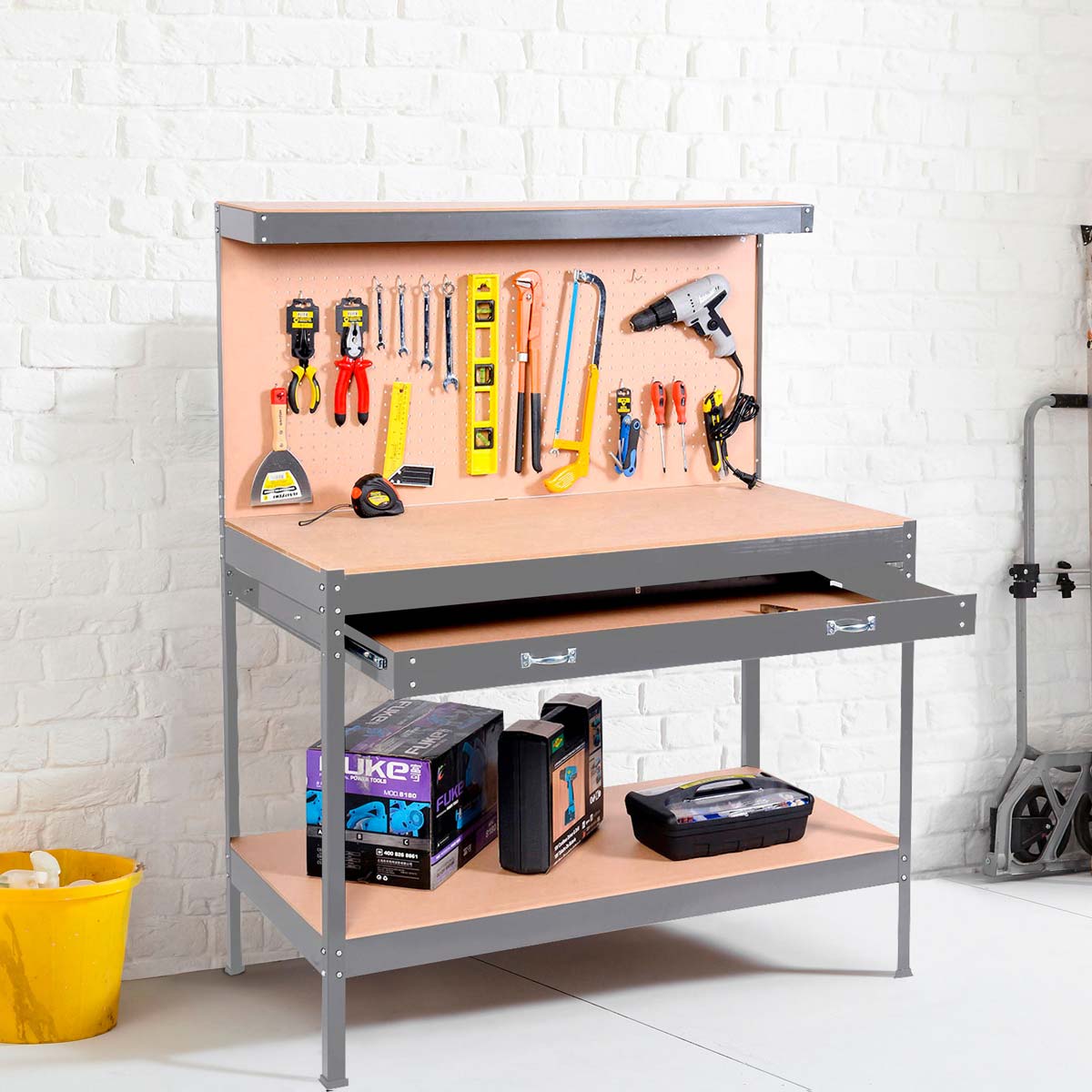 Grey Neo workbench featuring a heavy-duty steel pegboard, equipped with various tools, a drawer, and a lower shelf for storage, set against a white brick wall.