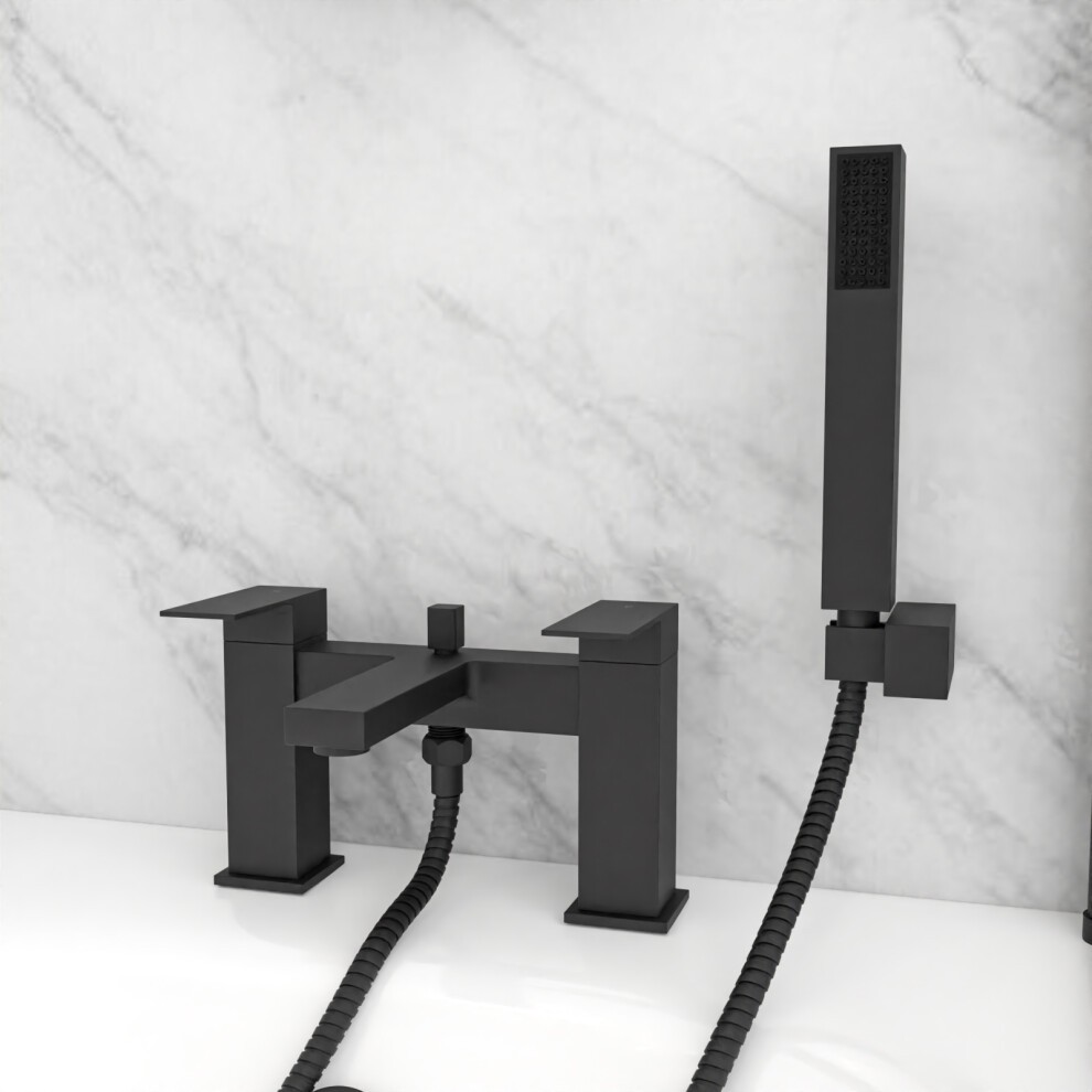 Modern matte black deck-mounted bath shower mixer with a square design, featuring two lever handles and a handheld shower handset, set against a marble background.