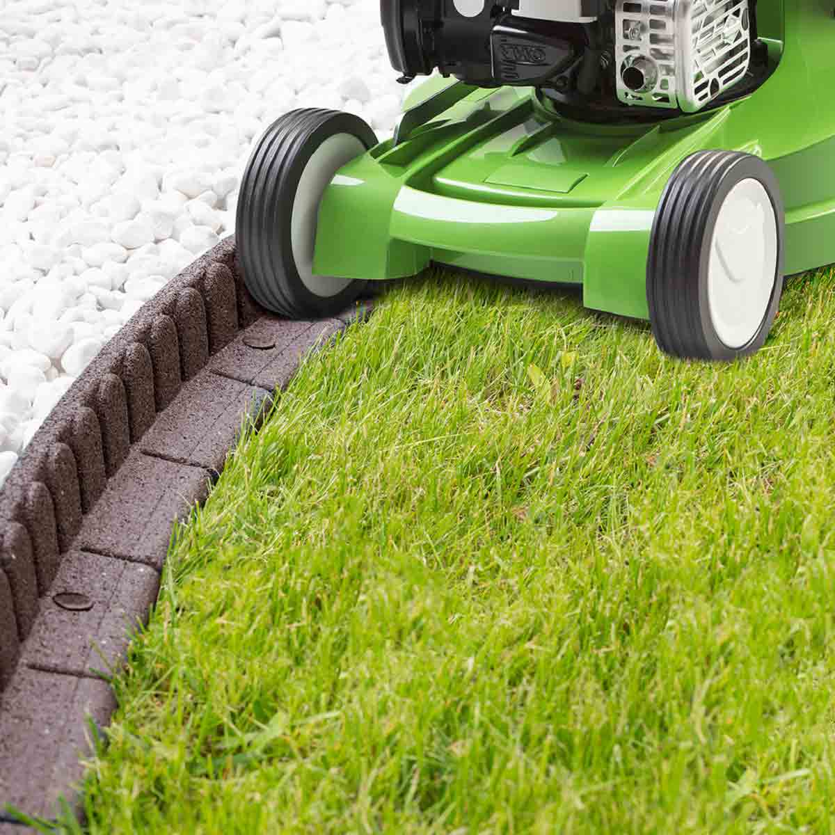 Brown lawnmower-friendly border edging made of durable material, featuring a curved design, surrounding lush green grass and white gravel.