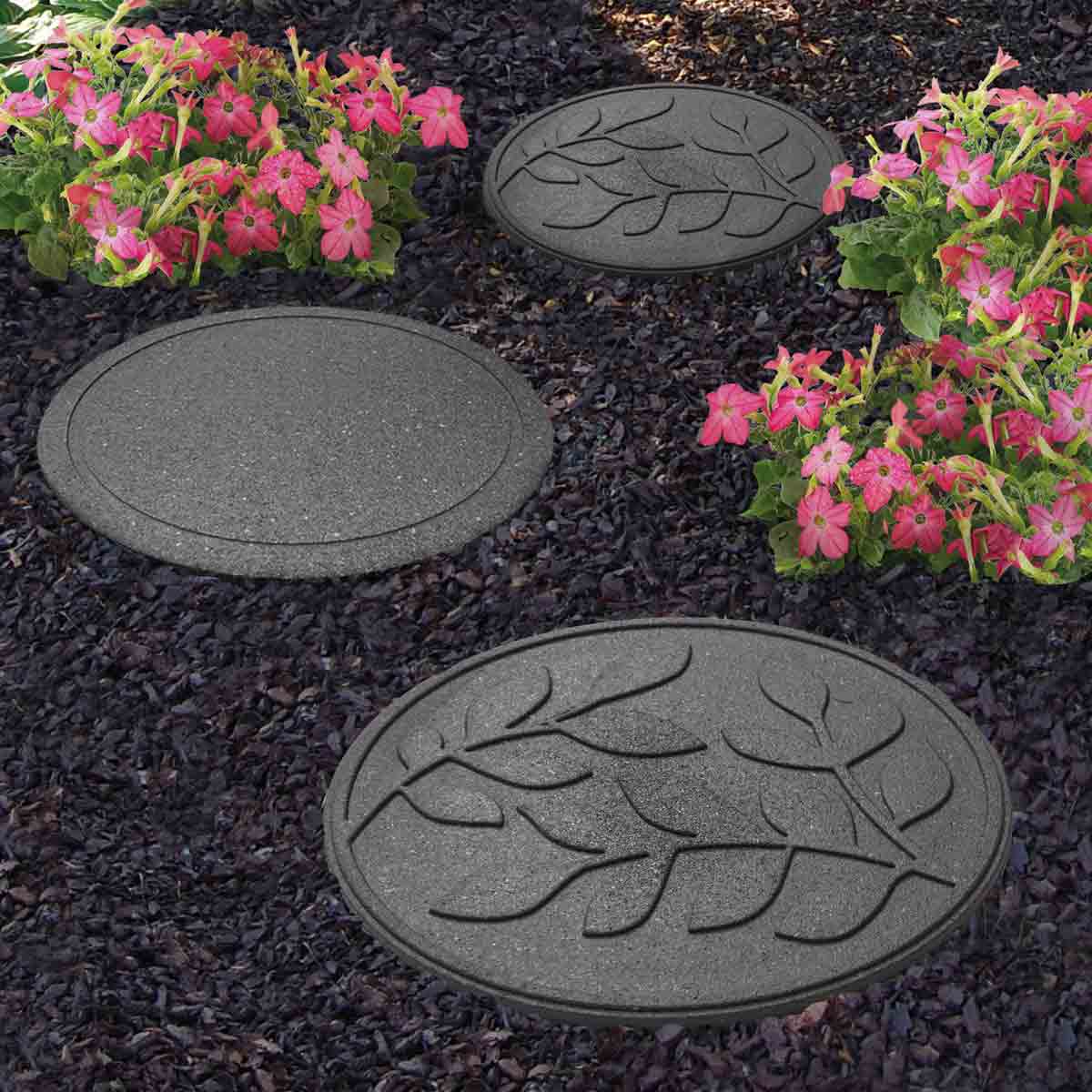Grey 45cm circular stepping stones with a leaf design, made from durable material, arranged among vibrant pink flowers on dark gravel.