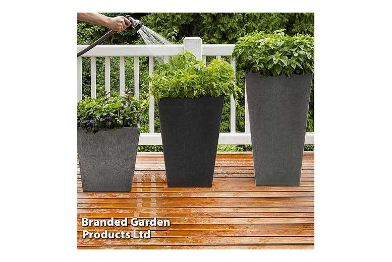 Steel grey Sonata planter by Primeur, 33cm tall, featuring a sleek, modern design with a textured finish, filled with lush green plants, set on a wooden deck.