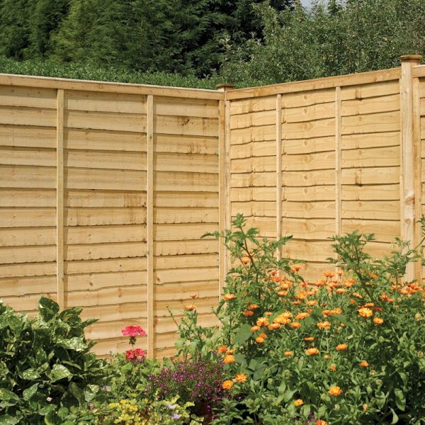 Rowlinson Lap Panel Pressure Treated Fence in natural wood finish, 6x4 size, featuring horizontal slats and sturdy vertical posts, surrounded by vibrant garden flowers.