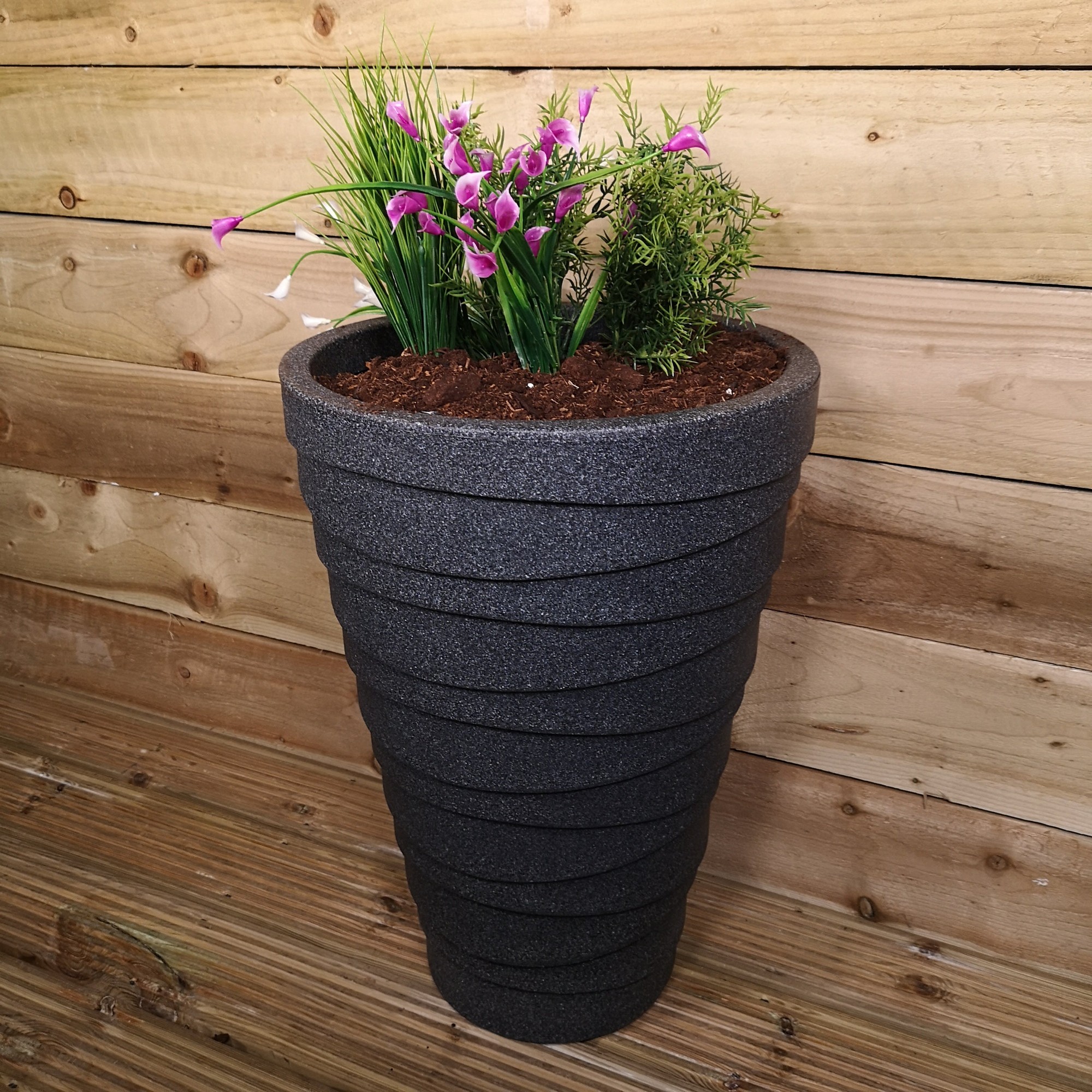 Medium grey ash color garden pot, 56cm tall and 38cm wide, featuring a textured design and filled with vibrant flowers and greenery against a wooden backdrop.