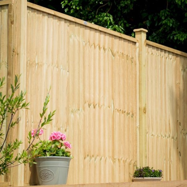 Grange Superior Closeboard Panel in green, featuring vertical wooden slats, a smooth finish, and topped with a decorative cap, with potted flowers in the foreground.