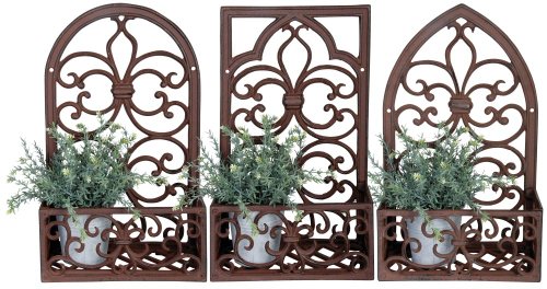 Brown metal window frame with intricate scrollwork design, featuring three flower planters with green foliage in white pots.
