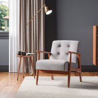 Gray upholstered tufted armchair with solid wooden frame and angled legs, placed on a light rug.